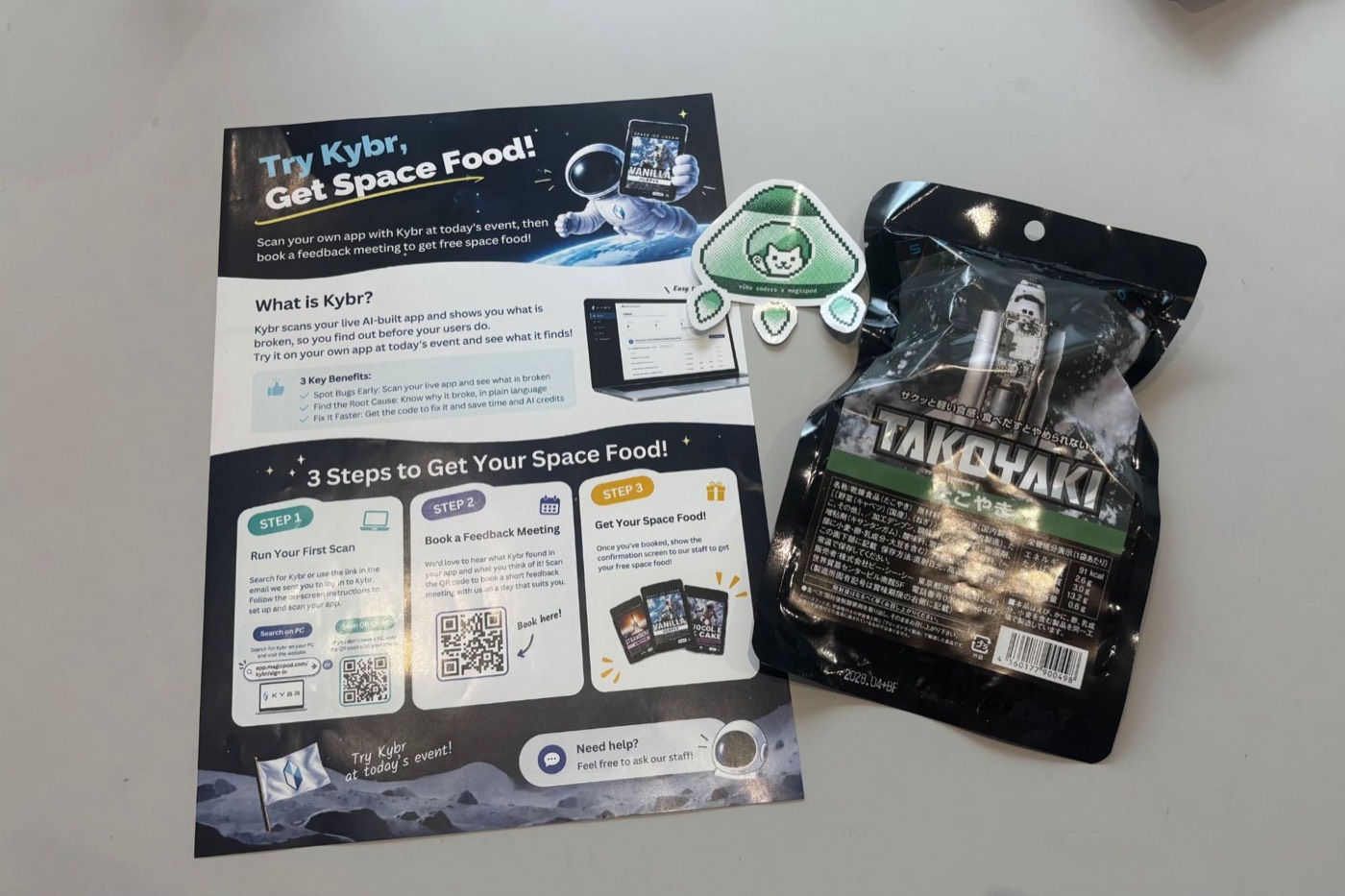 Try Kybr, Get Space Food campaign flyer next to a vibe coders × MagicPod sticker and a pack of freeze-dried takoyaki space food